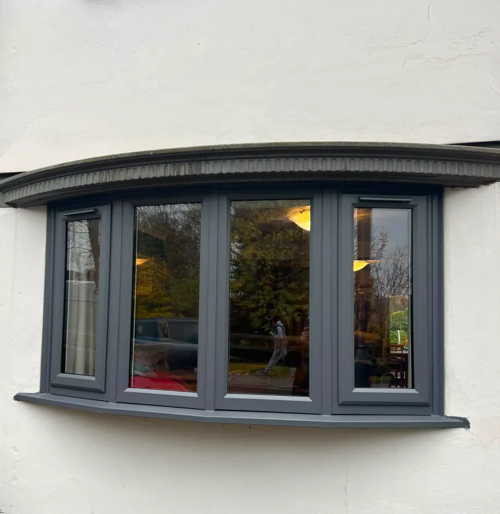 Anthracite-grey curved bow window on a rendered period home