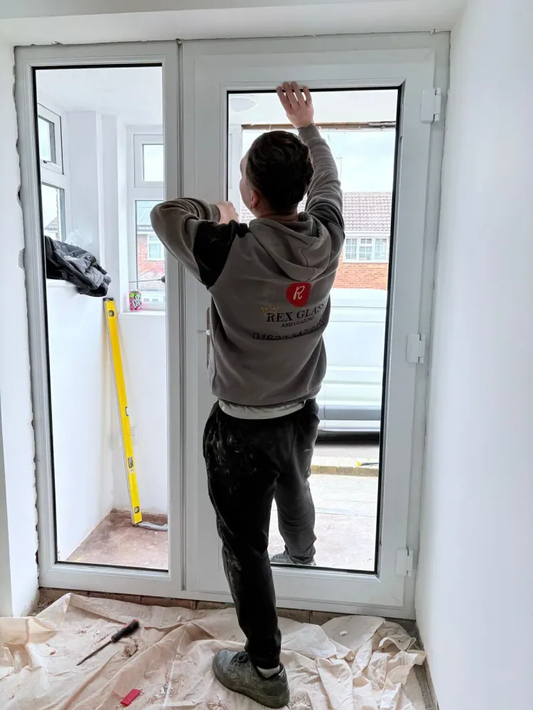 A Rex Glass and Glazing fitter installing a new white uPVC French door