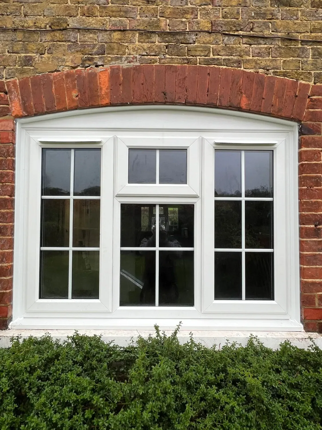 New white UPVC windows with astragal bars in a period brick home