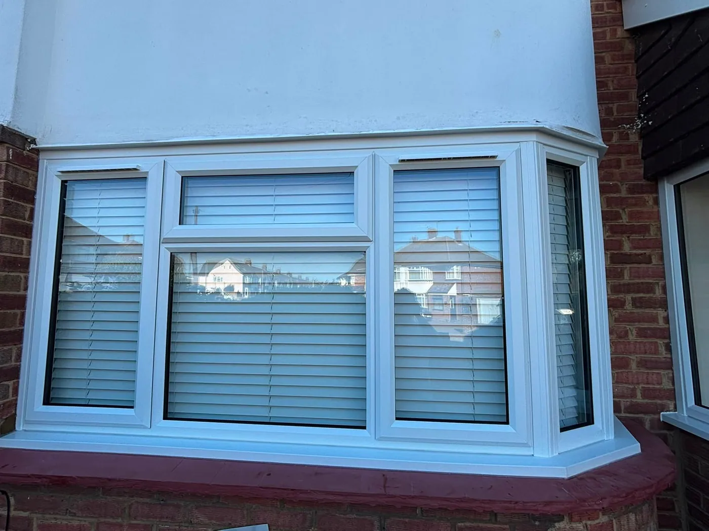 White UPVC bay window with three casements and integral blinds, fitted to a rendered semi-detached home