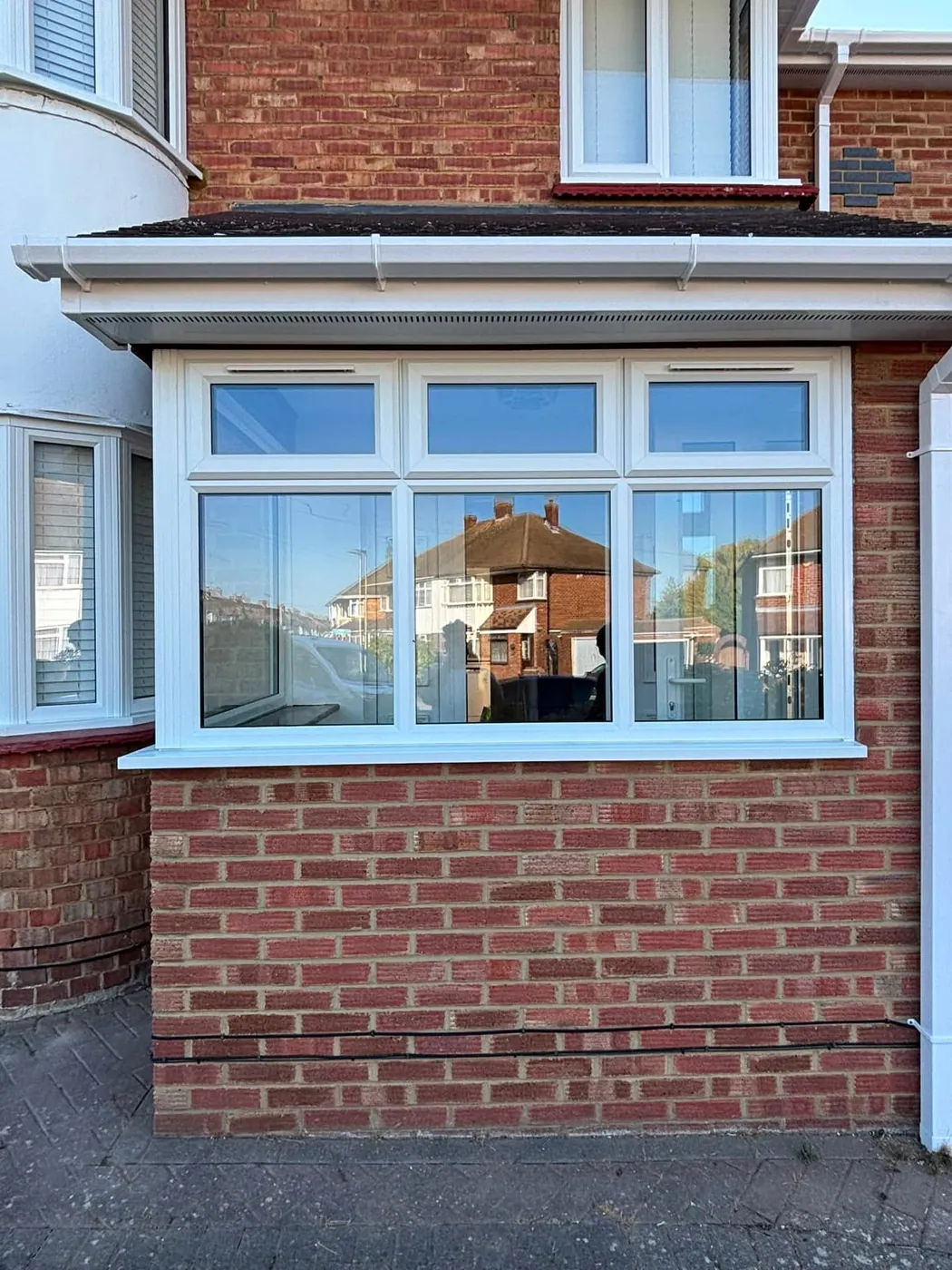 White UPVC casement window with three panes and top openers above new brickwork
