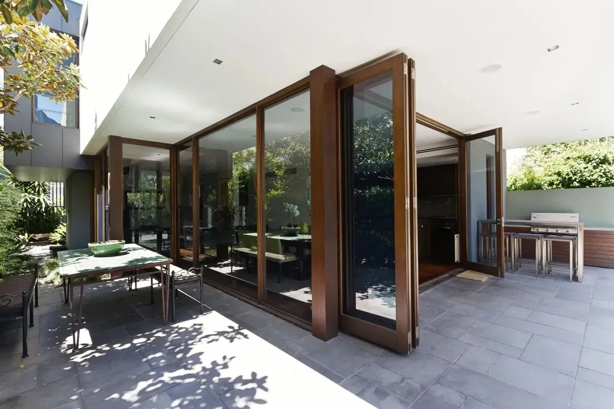 Oak-effect bifold doors folded back in a concertina, opening a room onto a paved terrace