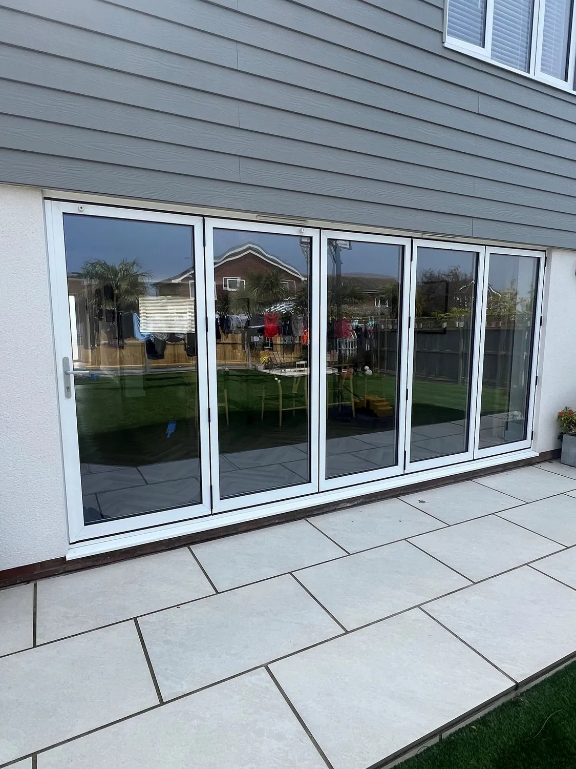 White UPVC bifold doors, five panels wide, closed across a patio opening