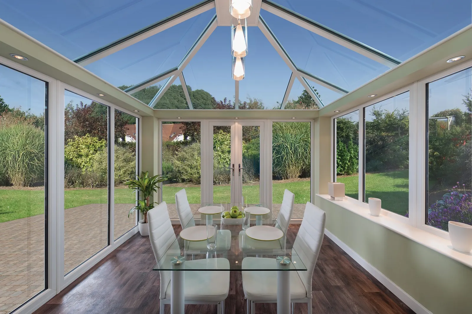 A room glazed on three sides with a fully glazed roof above a dining table, showing a large uninterrupted area of glass