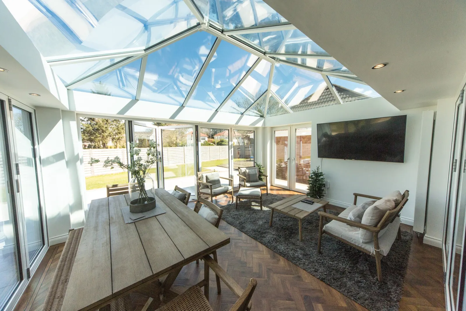 An open-plan dining and living room beneath a large white roof lantern