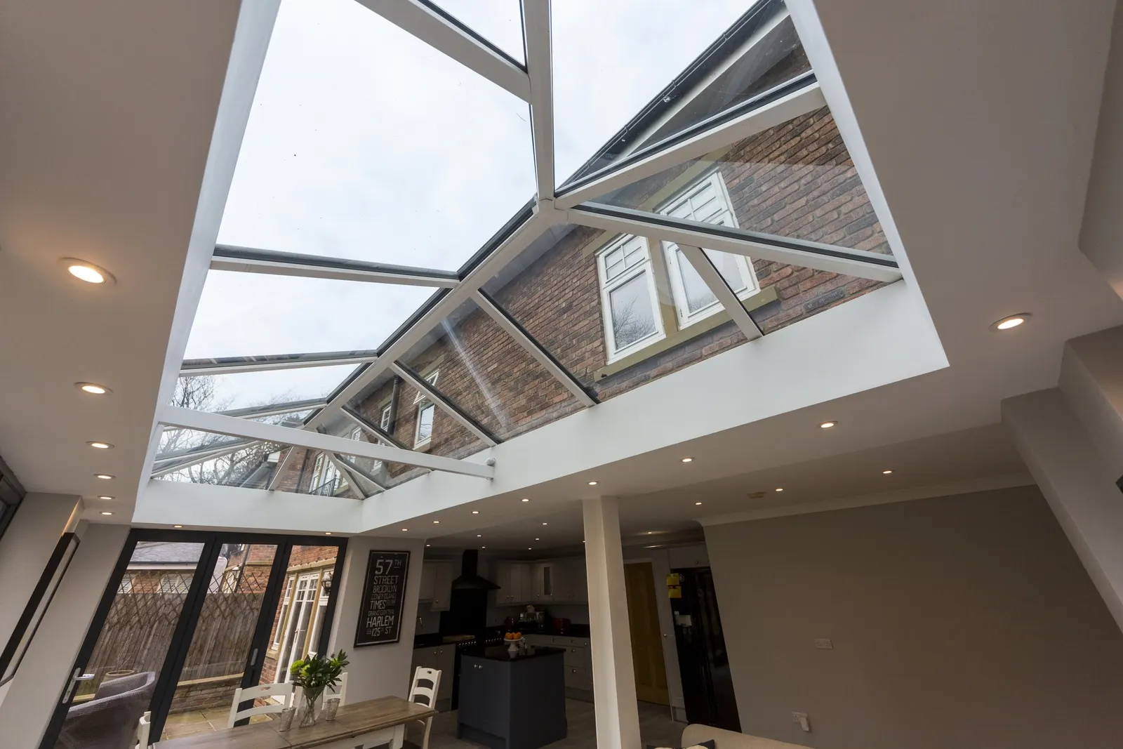 A white roof lantern seen from below, over an open-plan kitchen with anthracite bifold doors
