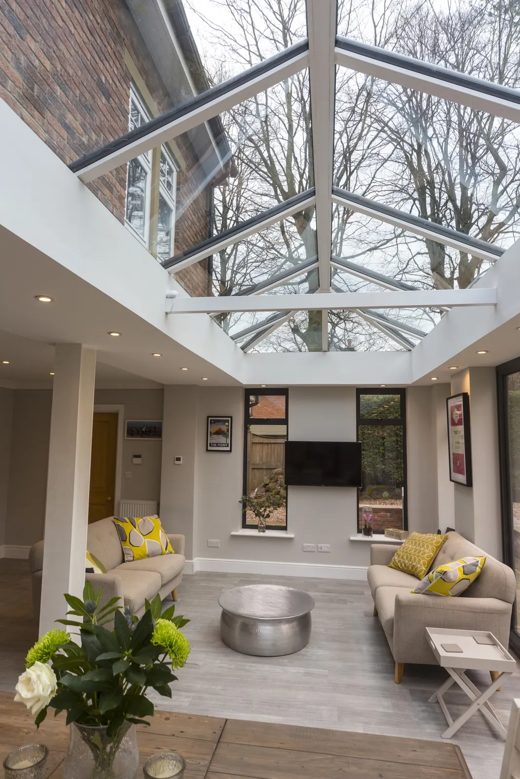 A finished lounge beneath a white roof lantern, with an exposed brick feature wall