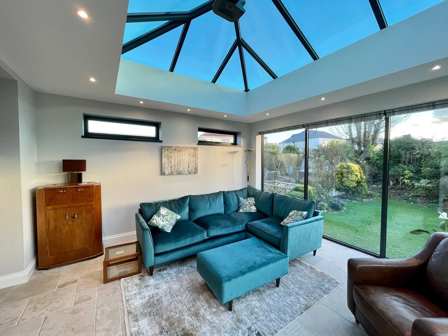 A three-panel anthracite sliding patio door run along one side of a lounge, stacking to one side