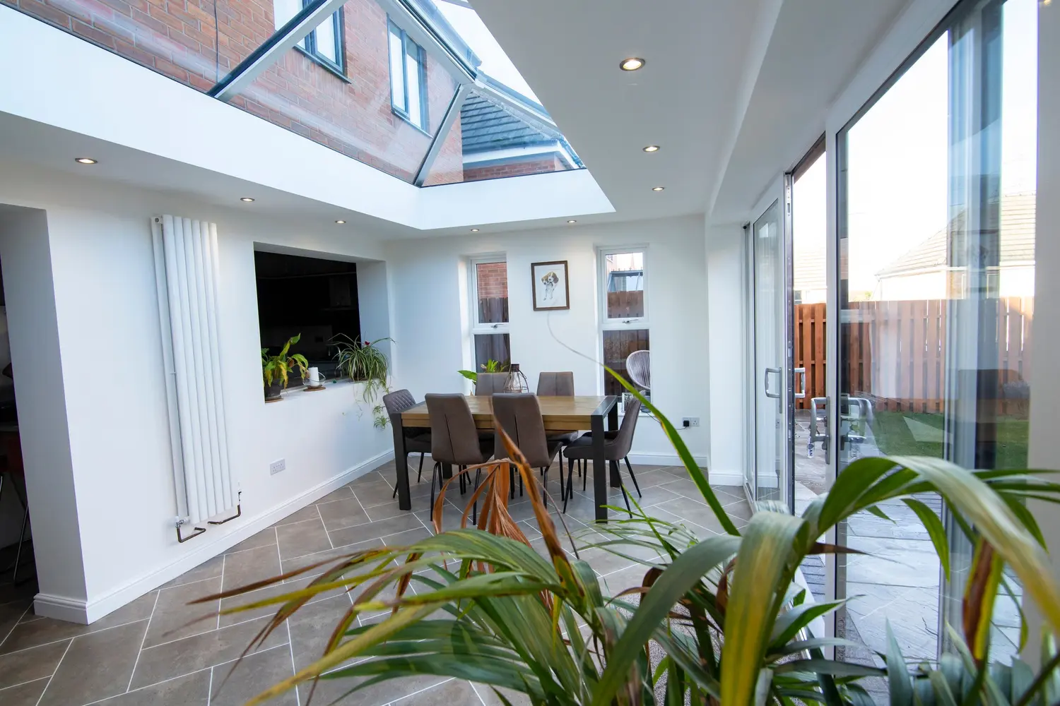 A glazed extension with a roof lantern over a dining area and sliding patio doors onto the garden