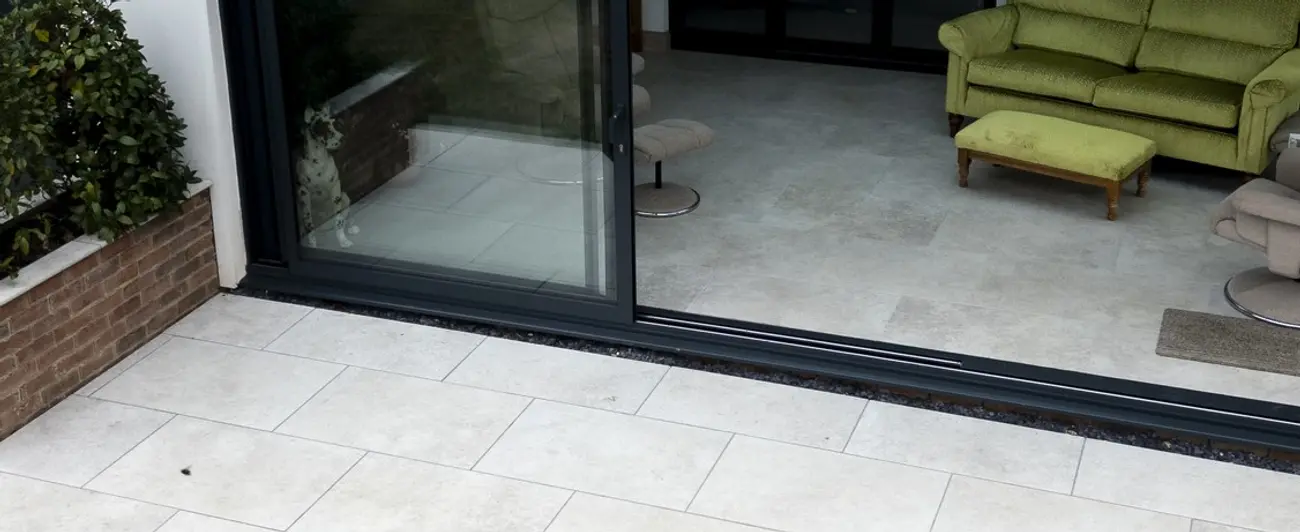 Threshold detail of a two-track sliding patio door, with one pane parked behind the other and both runners visible