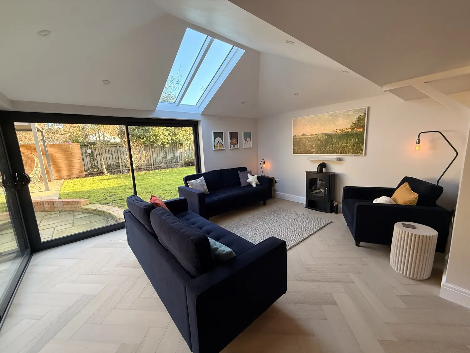A lounge in a glazed extension, with anthracite doors onto the garden and a slim roof light set into the vaulted ceiling