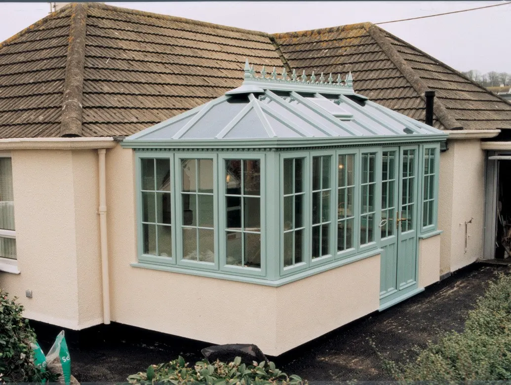 Sage green UPVC frames and casement windows across a conservatory on a rendered home