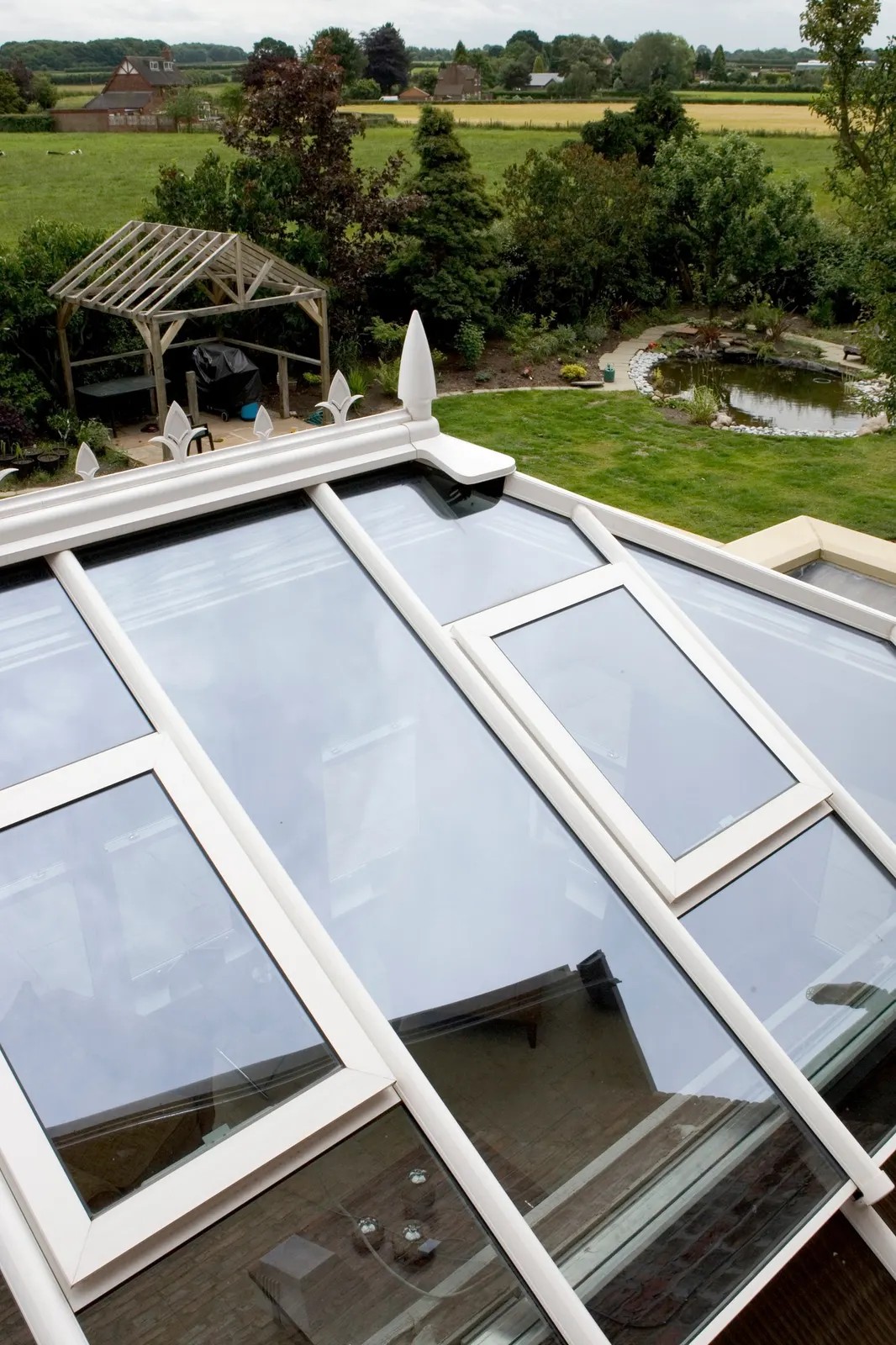 A white glazed roof lantern photographed from above, garden and fields beyond