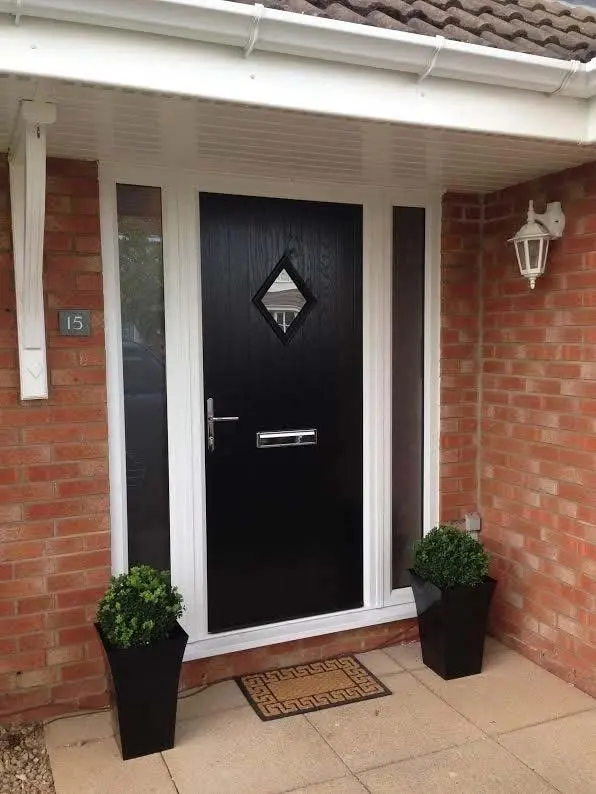 A black composite front door with diamond glazing, in a brick porch