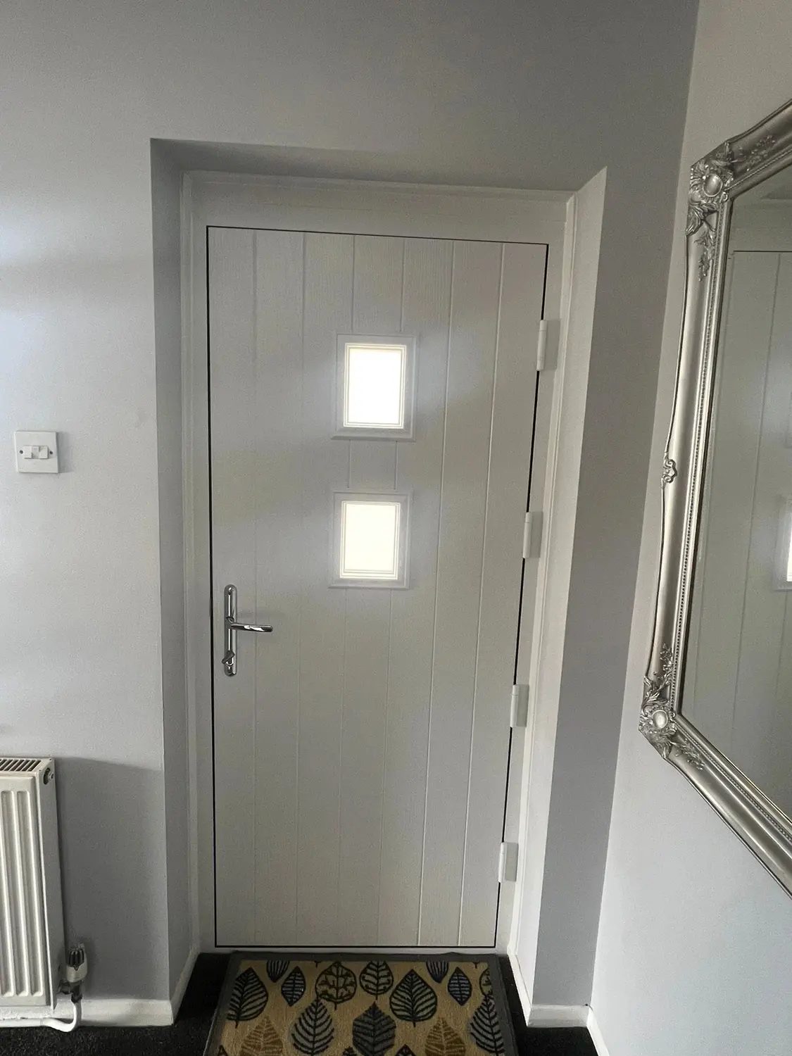 A cream composite front door seen from inside the hallway, with two glazed panes