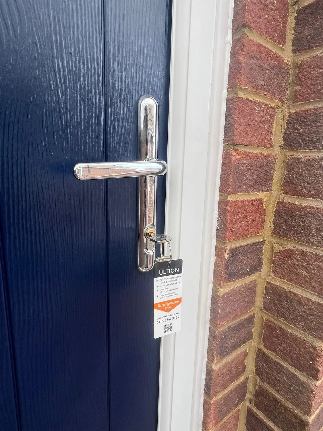 Close-up of a navy composite door with a chrome lever handle and an Ultion lock cylinder