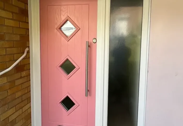A salmon pink composite door with diamond glazing and a glazed side panel