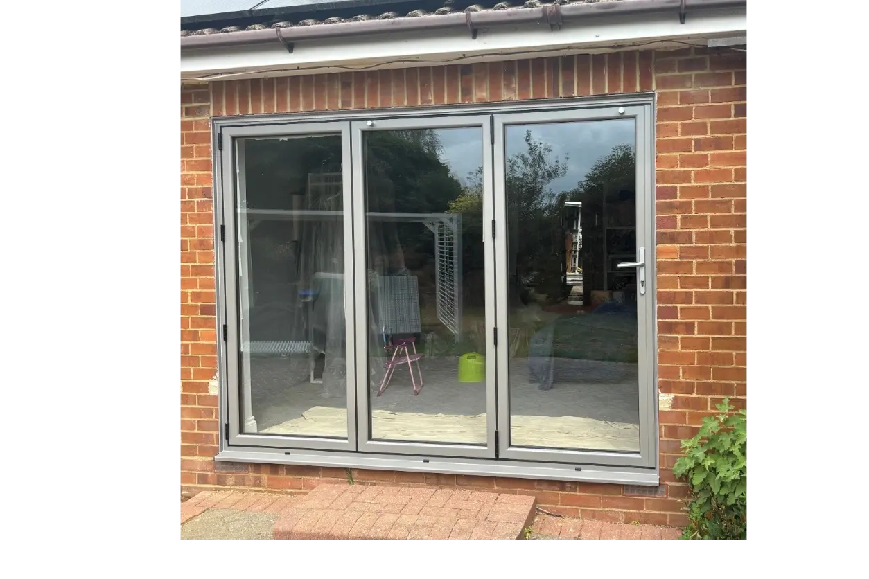 Grey aluminium multi-panel doors closed across a wide opening in brickwork