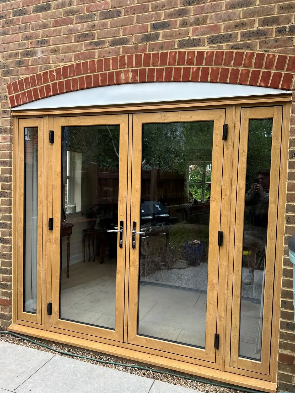 Light oak French doors set under a brick arch, opening onto a patio