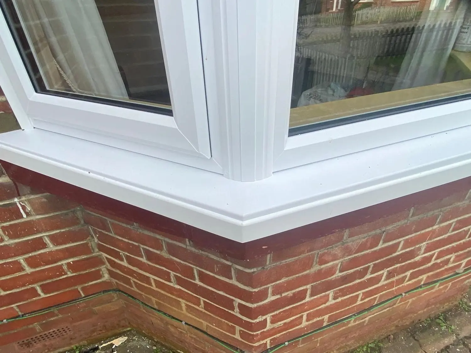Corner detail of a white UPVC bay window, showing the frame and the sill return