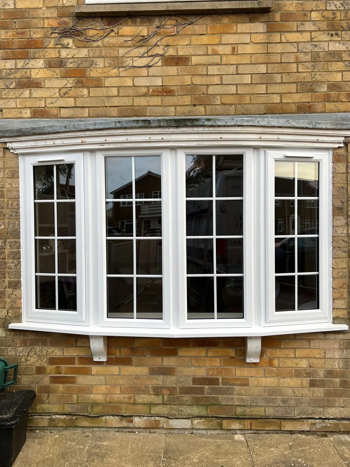 A white UPVC bay window with Georgian bars, on a buff brick house