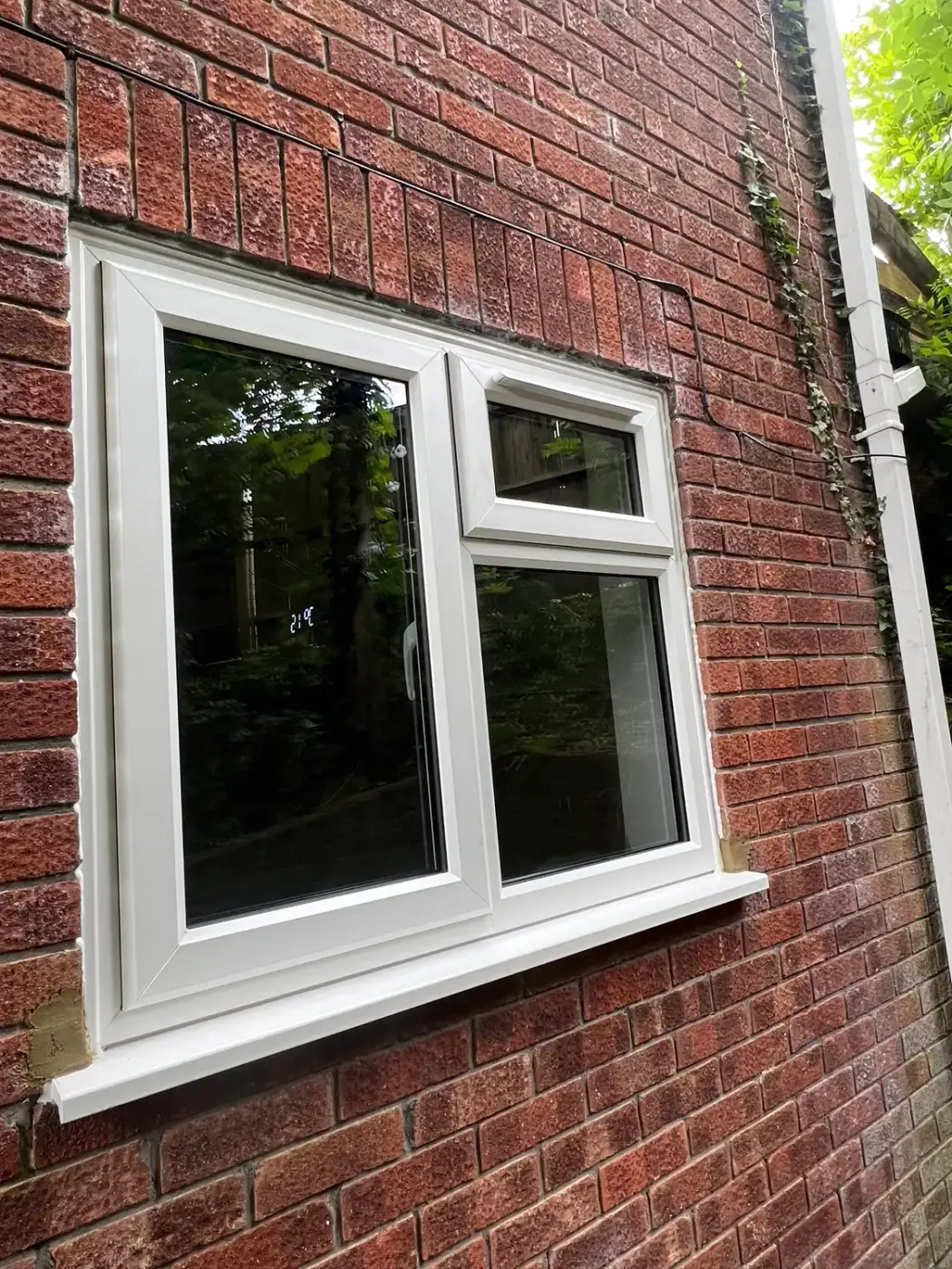 A white UPVC casement window with a side opening light, in red brickwork