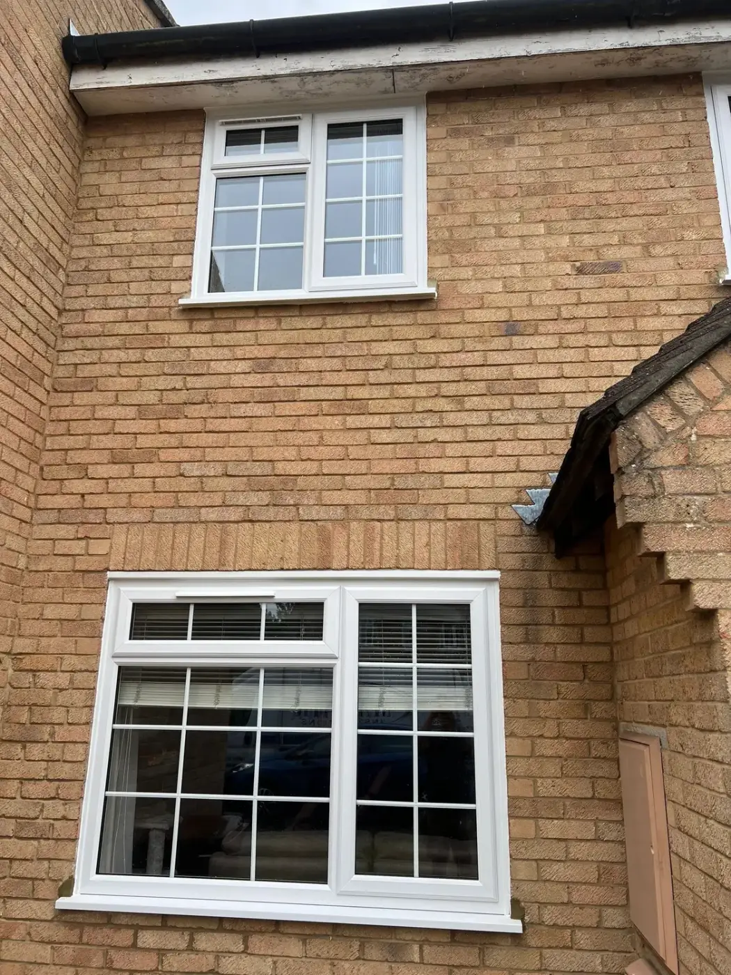Two white UPVC windows with Georgian bars on a brick house