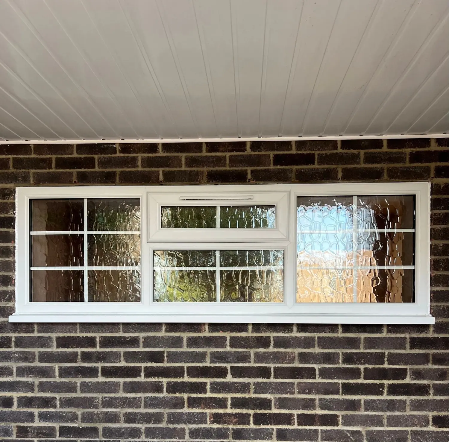 A run of white UPVC windows with Georgian bars and obscure glazing, above new brickwork